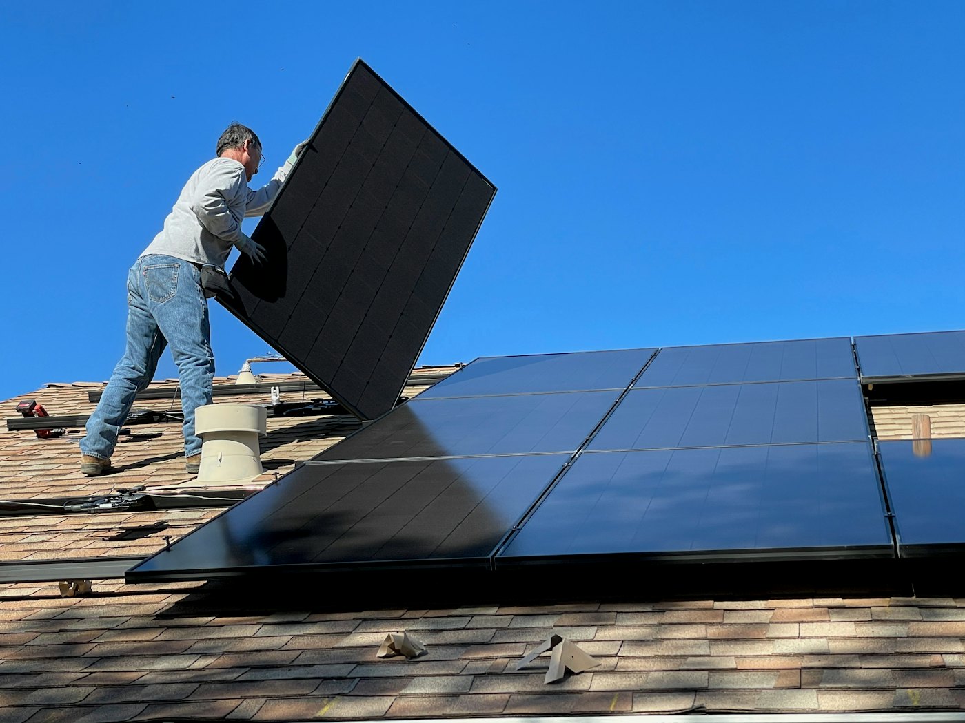Technician placing a solar panel on a residential roof